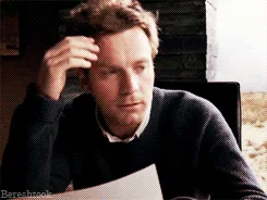 A six-panel image sequence shows a man in a dark sweater sitting at a table, initially looking thoughtful while holding a…