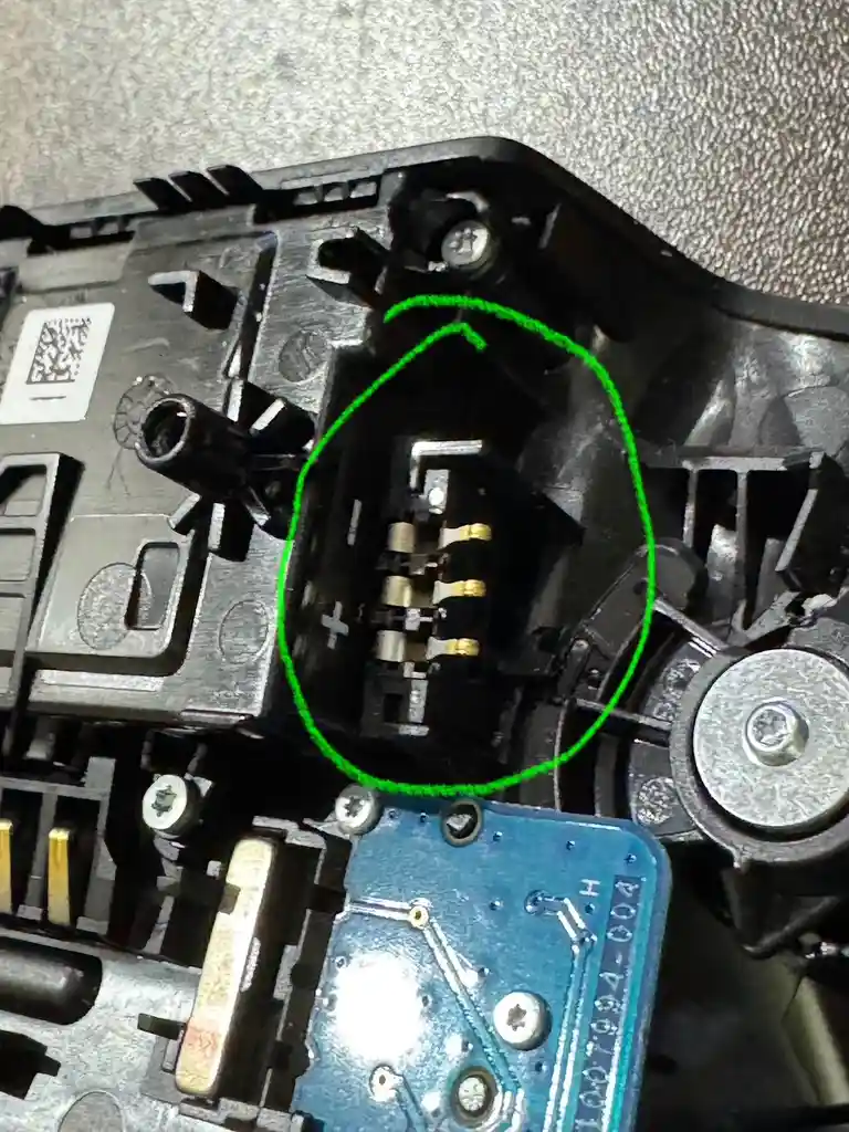 a close-up photo of the internal mechanism of a printer cartridge, with a green circle highlighting the metal electrical…