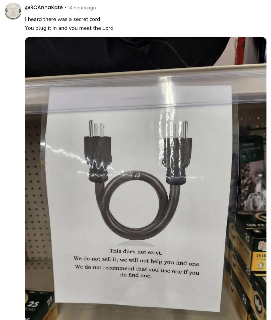 A printed sign in a store displays a black, coiled electrical cord with two plugs on each end, resembling a looped cord. The…