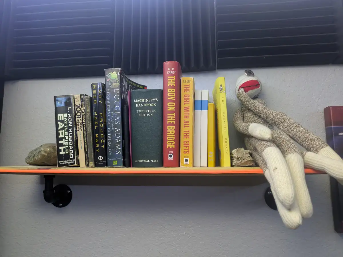 A bookshelf holds various books including 'Machinery's Handbook', 'The Boy on the Bridge', and 'The Girl with All the…