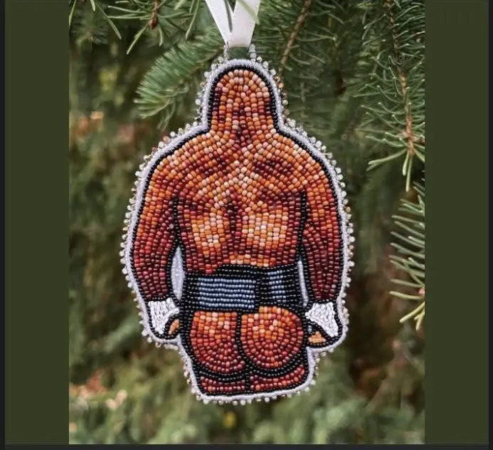 A beaded Christmas ornament shaped like a muscular boxer from behind, hanging on a pine tree, with the text 'i'm not a fan…