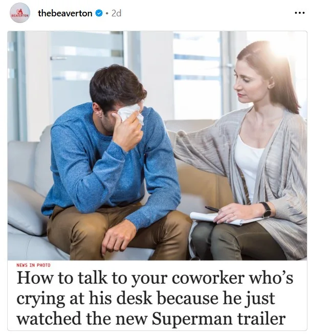 A man in a blue sweater sits on a couch, visibly upset and wiping his eye with a tissue, while a woman in a cardigan sits…