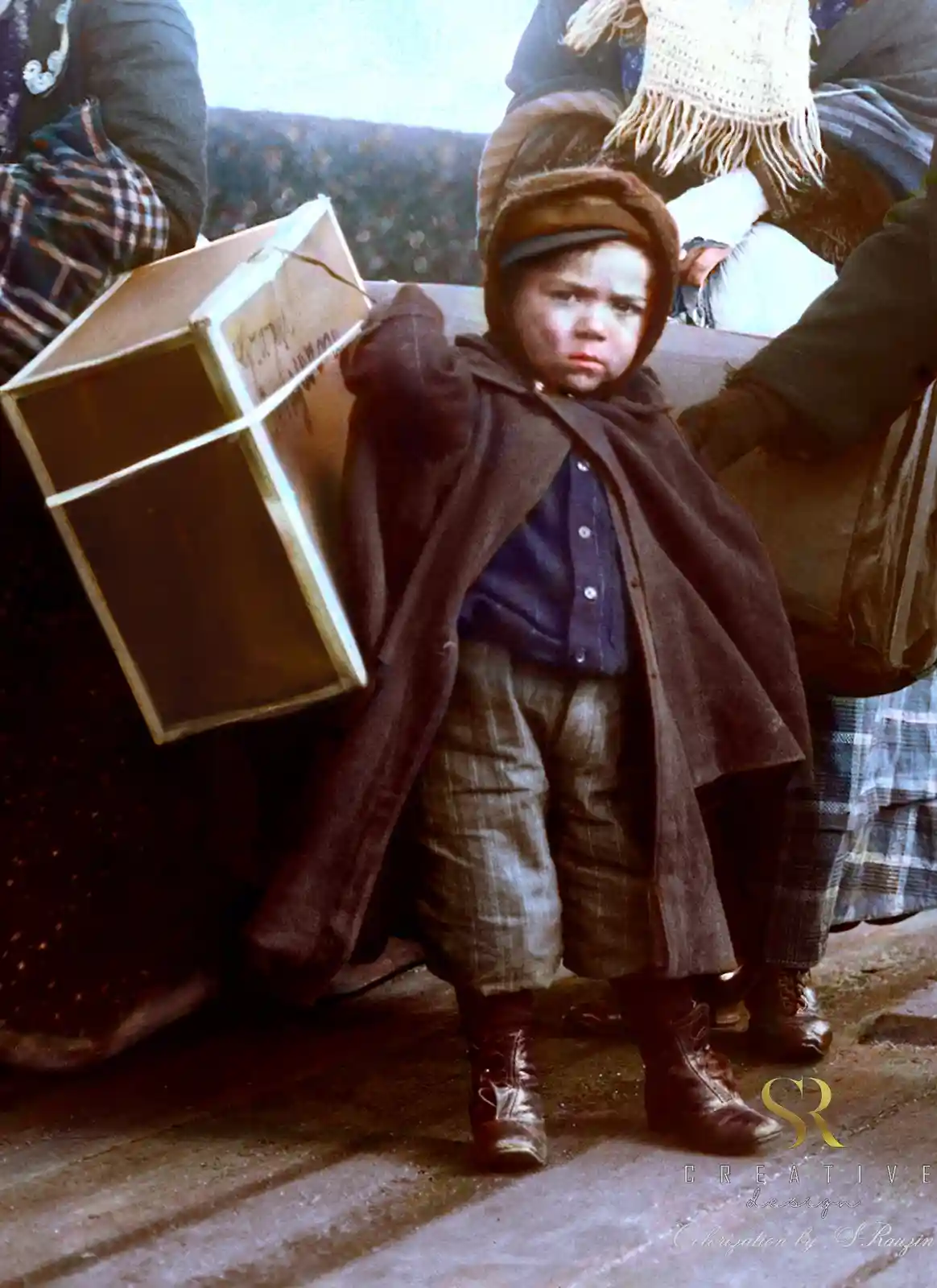 A colorized historical photo shows a young child in worn clothes and a hat, carrying a large cardboard box while looking…
