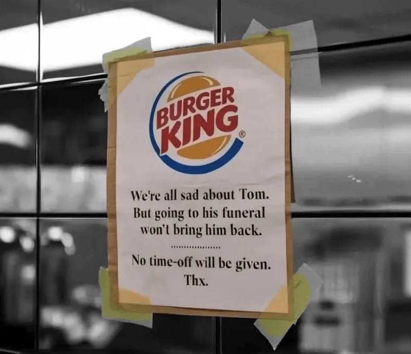 A Burger King sign taped to a glass door in black and white, featuring the Burger King logo and text stating that employees…