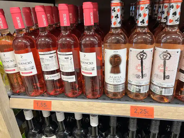 A supermarket shelf displays two types of rosé wine: 'Fidencio Rosado' bottles with red caps priced at 1.55€ and 'Alicia en…
