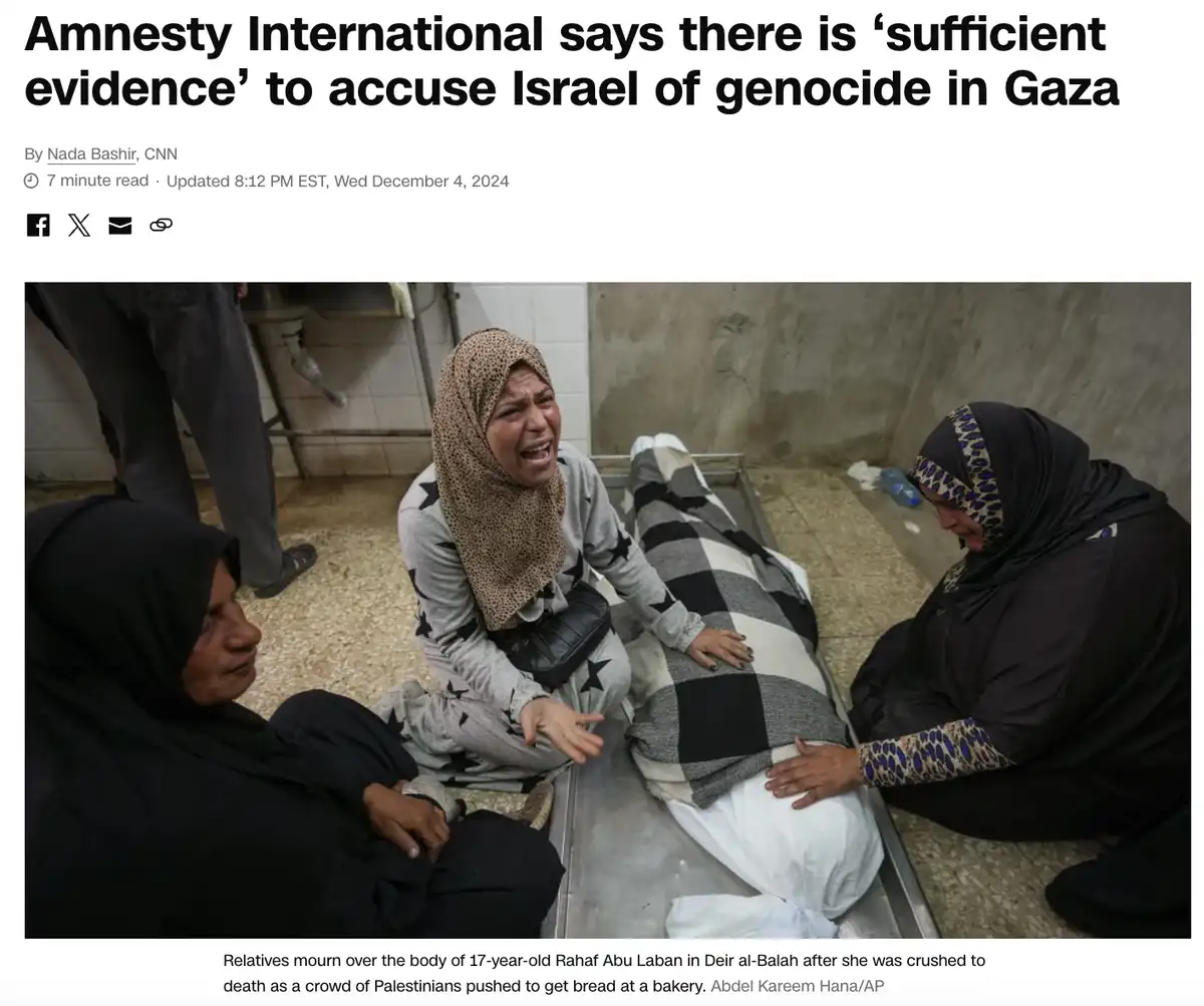 A somber photo shows three women mourning around a body on a metal gurney in a simple room. The central woman, wearing a…