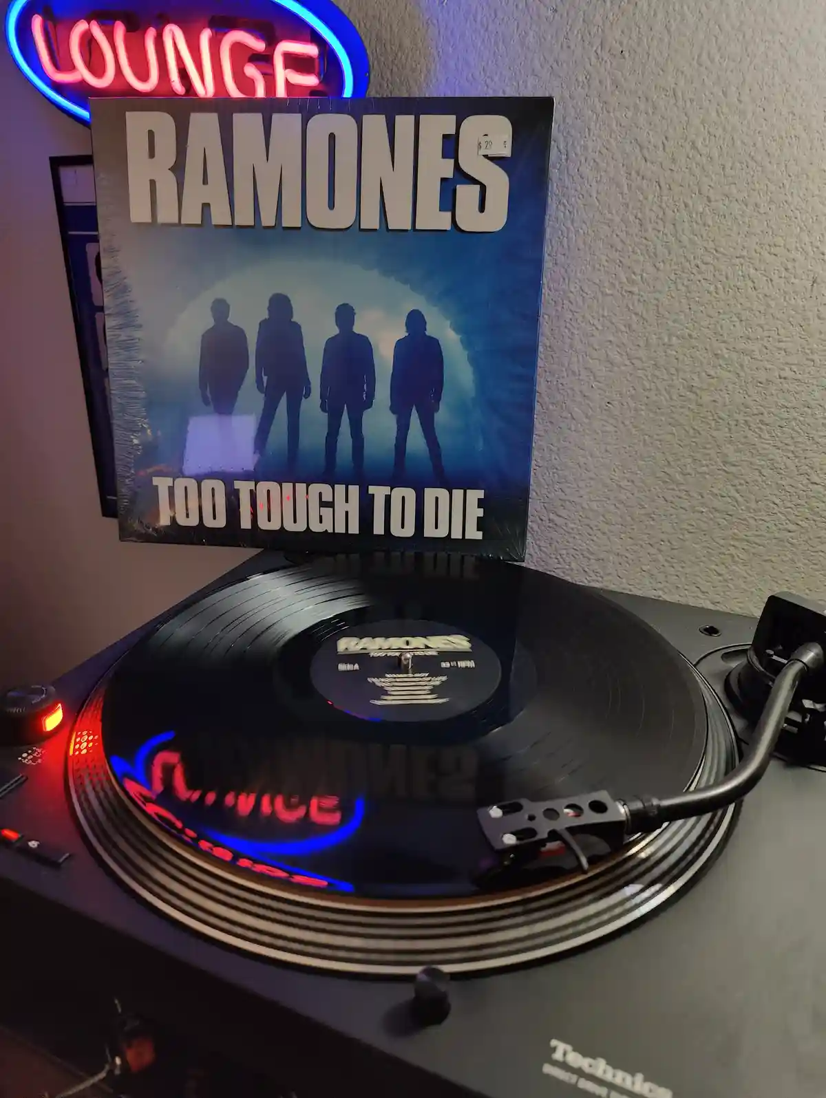 A vinyl record of the Ramones album 'Too Tough to Die' is playing on a Technics turntable, with the album cover standing…