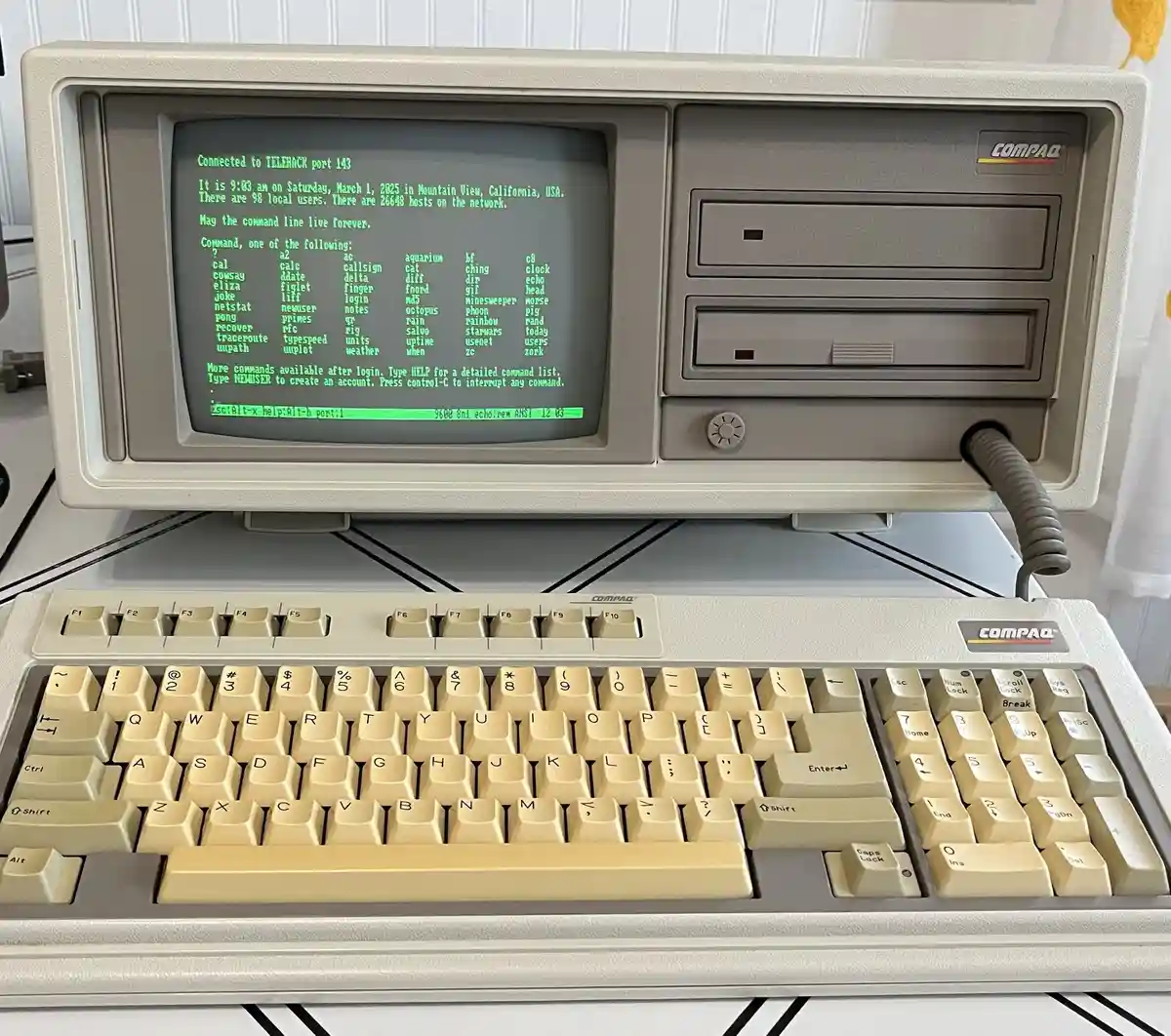 A beige Compaq portable computer with an integrated CRT monitor and keyboard, displaying a green-on-black terminal…