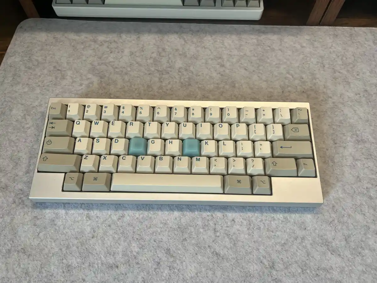 A close-up photo of a beige mechanical keyboard with two light blue keys, 'G' and 'H', highlighted in the middle row. The…
