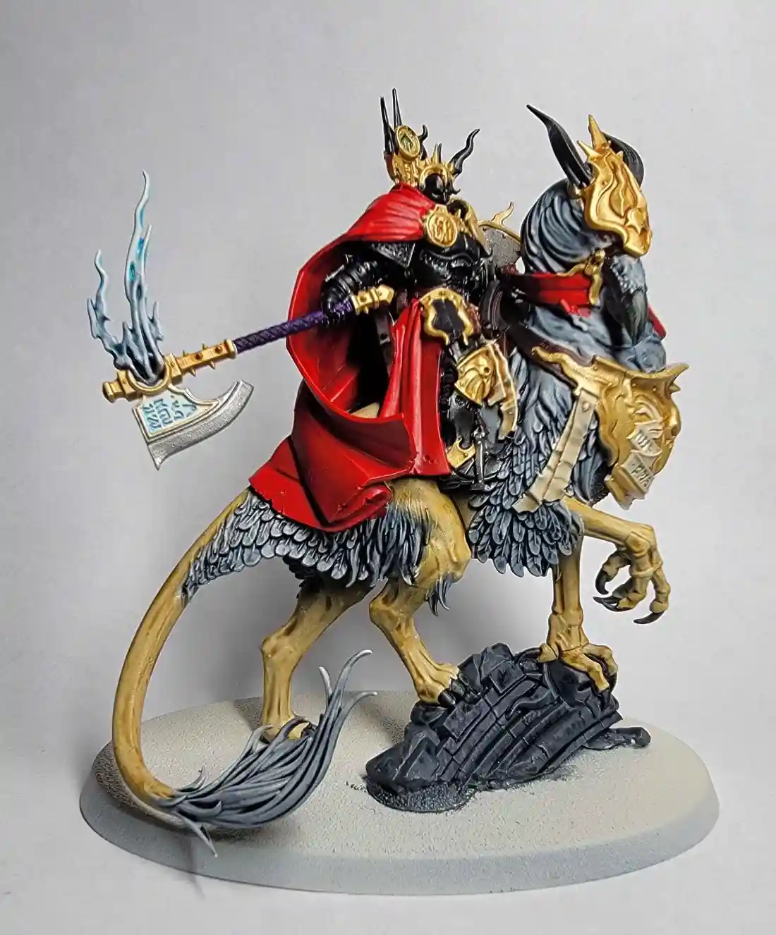 A highly detailed, painted miniature figure of a demonic rider on a winged, armored beast, wielding a flaming axe. The rider…