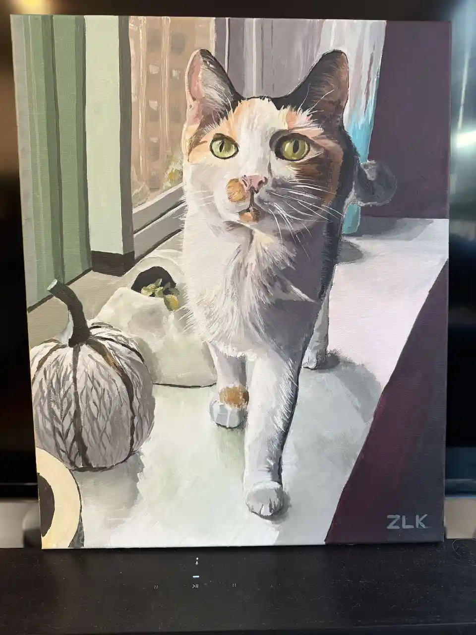 A painted portrait of a calico cat with green eyes standing indoors next to a small pumpkin, looking directly at the viewer…