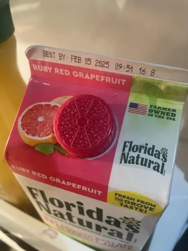 A close-up photo of a Florida's Natural Ruby Red Grapefruit juice carton, showing its 'BEST BY' date printed on the top edge…