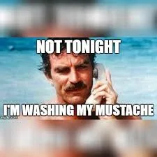 A man with a mustache is on a phone call, looking serious, against a blurry beach background. The text overlaid in white…