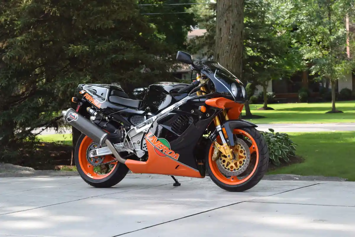 A black and orange sport motorcycle, branded 'INVERDA' and 'FORMULA', is parked on a concrete driveway in a suburban yard…
