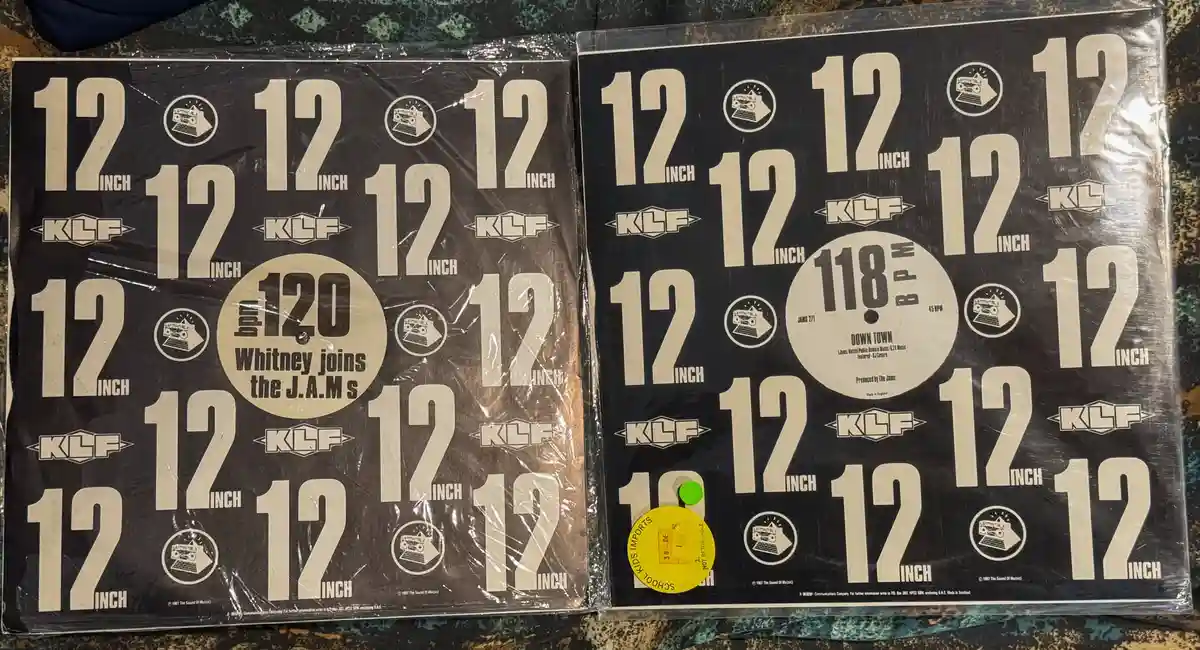 Two 12-inch vinyl records in their original shrink wrap, both featuring the KLF label. The left record has a central label…