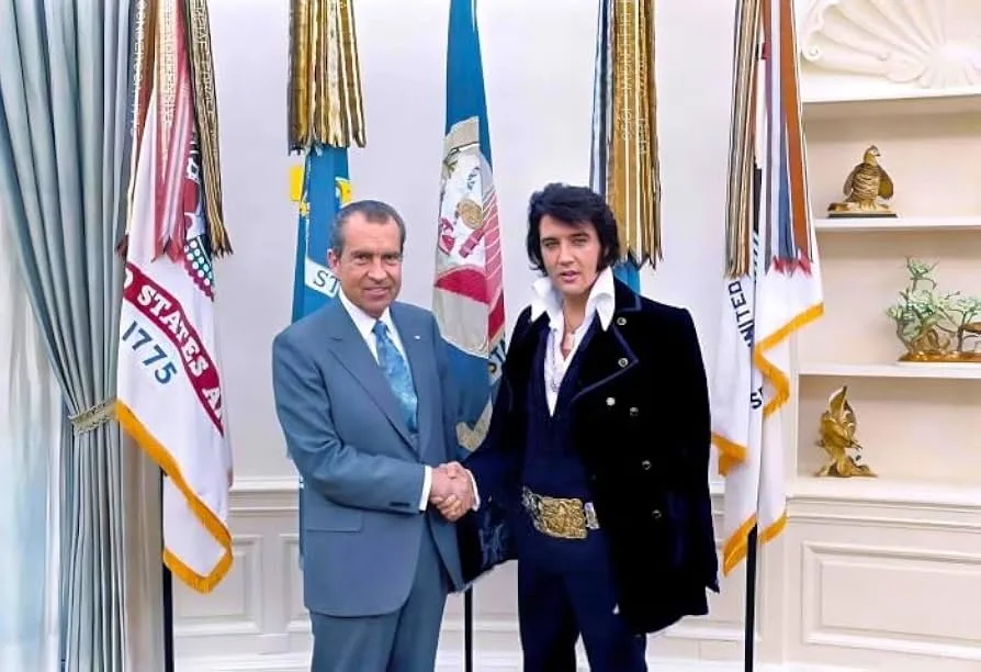 A photo shows Richard Nixon in a suit shaking hands with a man in an Elvis Presley costume, standing in front of flags and…