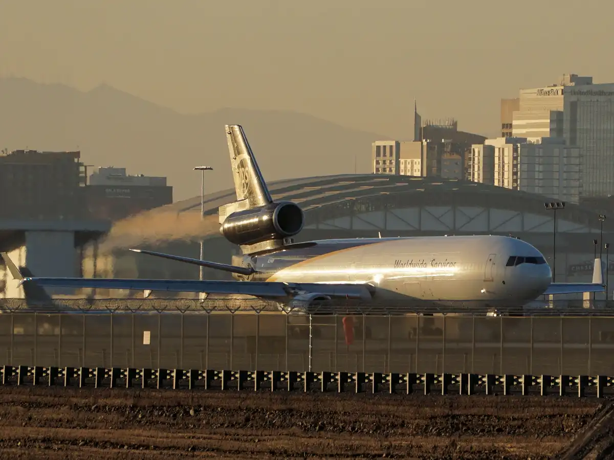 A silver NASA-owned McDonnell Douglas MD-11 cargo plane, marked 'Worldwide Services', is shown on an airport tarmac with…