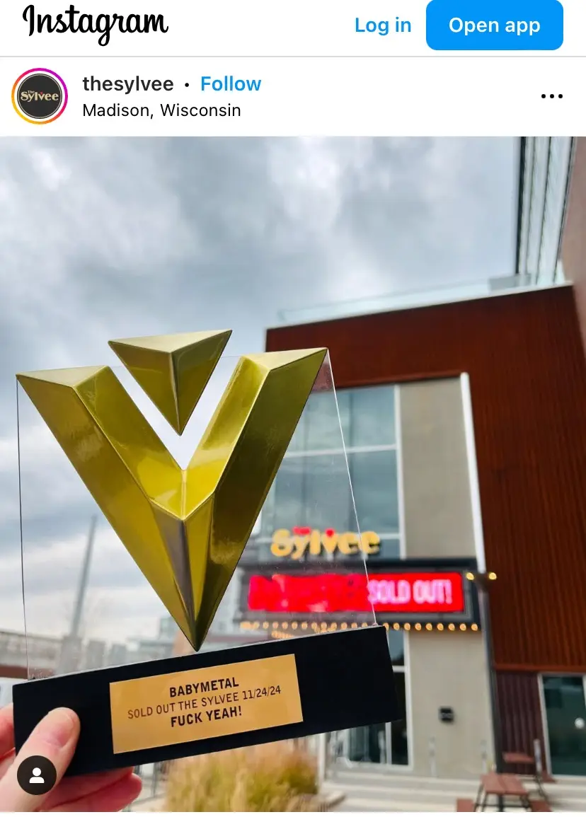 A person holds a clear acrylic award with a gold 'V' logo and a plaque that reads 'BABYMETAL SOLD OUT THE SYLVEE 11/24/24…